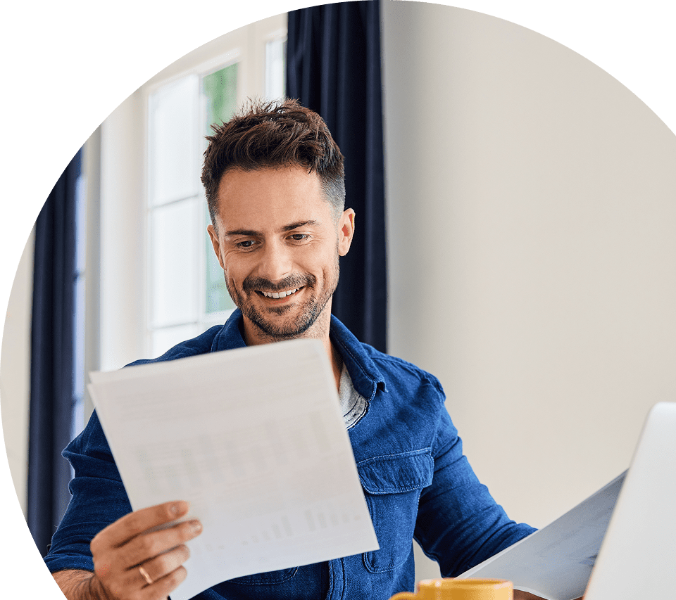Ellipse 12 Man smiling while reading papers at desk.
