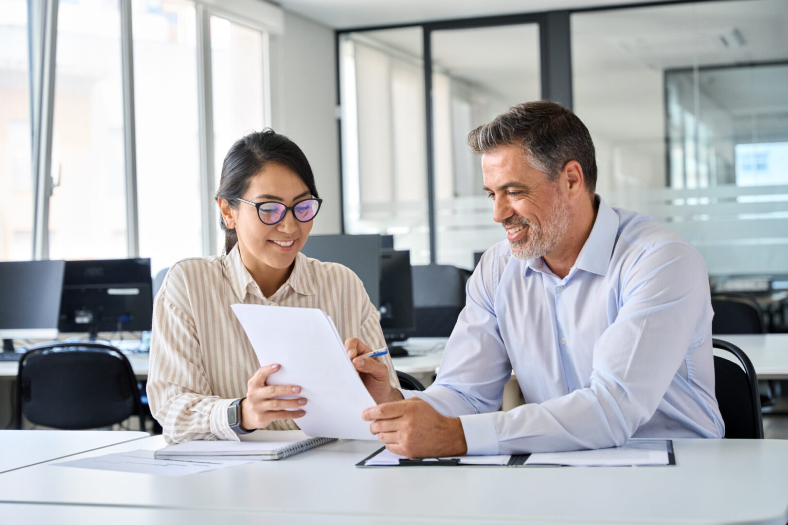Diverse professional colleagues discussing financial papers working in office. Two colleagues discussing documents in office.