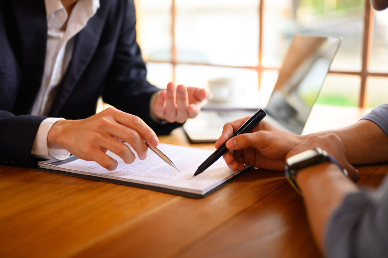 Closeup lawyer or insurance agent pointing at contract showing male client where to signature sign Two people discussing documents with pens.