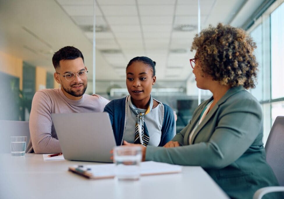 Three people discussing around a laptop.