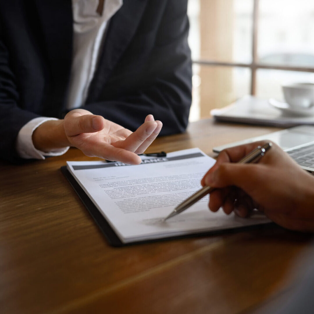Cropped shot of insurance agent showing where to sign a contract during meeting Two people discussing document in an office.